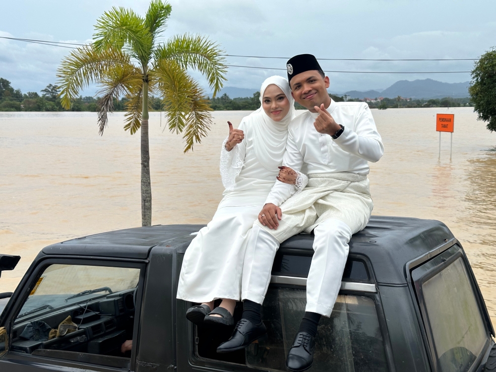 The couple took their wedding photos navigating flooded areas by boat and four-wheel drive. — Bernama pic