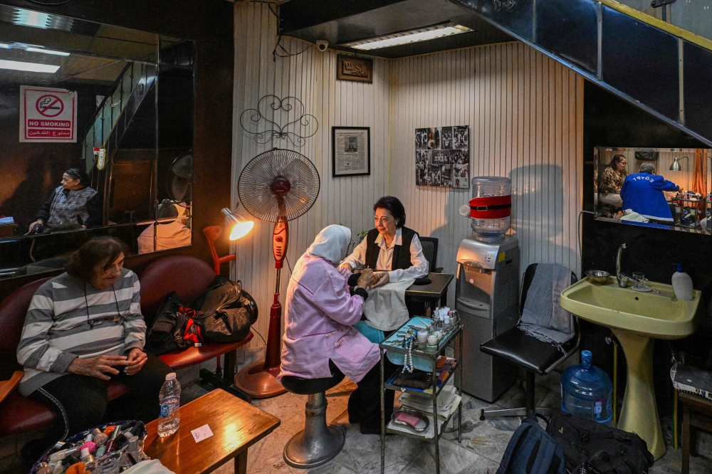 A client receives a manicure at Madam Lucie's manicure shop in downtown Cairo on November 18, 2024. Decades ago, the shop's seats were occupied by the likes of Nobel laureate Naguib Mahfouz, international singing sensation Dalida and cinematic heartthrob Omar Sharif, all of whom sought the now 88-year-old manicurist's expert hand. — AFP pic