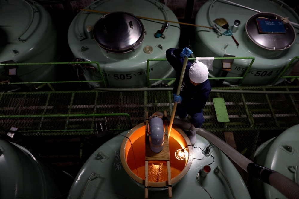 A brewer using a long paddle stirs the mixture of rice, Koji, water and yeast starter inside a giant tank as a part of the fermentation process to brew sake, a traditional Japanese rice wine, at Ishikawa Shuzou, or Ishikawa Brewery, in Fussa, western portion of Tokyo, November 25, 2024. — Reuters pic