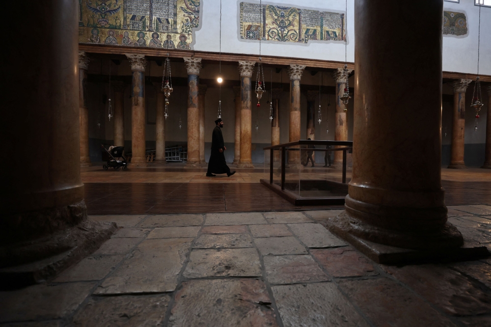 Orthodox priest Issa Thaljieh walks in the Church of the Nativity with no tourists in sight. — Reuters pic