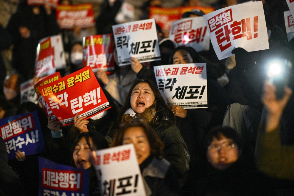 People take part in a protest calling for the resignation of South Korea President Yoon Suk Yeol at the National Assembly in Seoul on December 4, 2024. Thousands marched on parliament in South Korea's capital on December 4, joining a bid by the country's opposition to impeach President Yoon Suk Yeol after his extraordinary but short-lived imposition of martial law. — AFP pic