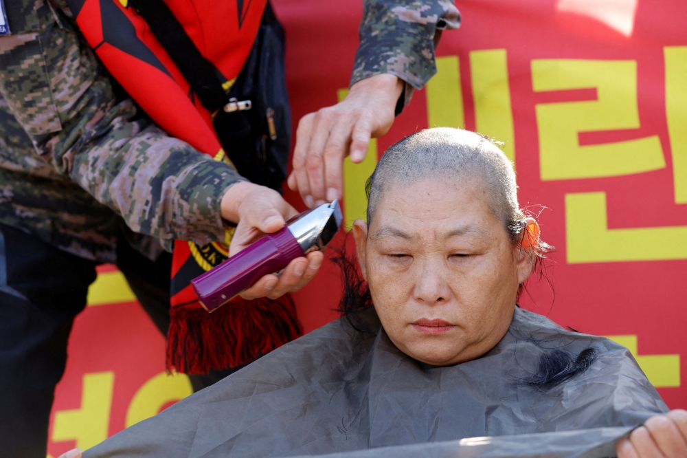 The wife of a South Korean marine veteran, gets her head shaved during a rally demanding South Korean President Yoon Suk Yeol's removal from power, in front of the presidential office, in Seoul, South Korea, December 5, 2024. — Reuters pic  