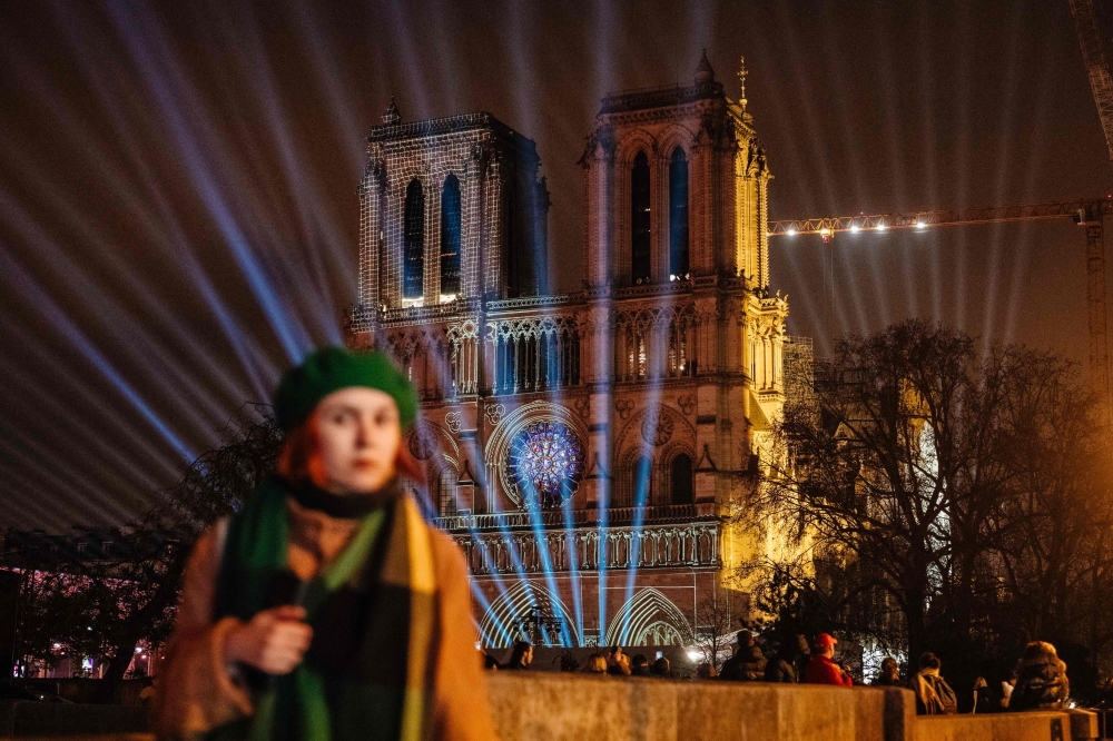 A pedestrian walks in front of the Notre-Dame de Paris cathedral illuminated in Paris on December 4, 2024, before its reopening on December 7, 2024. — AFP pic