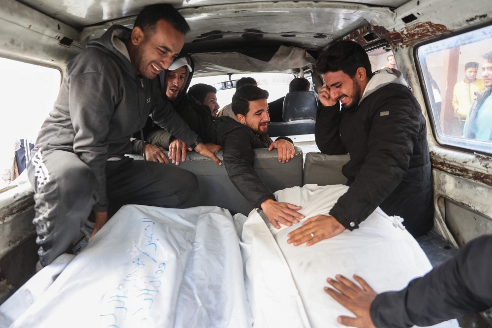 Palestinian men cry as bodies of victims of an Israeli strike in Gaza City's Daraj neighbourhood are transported, on December 5, 2024, amid the ongoing war between Israel and Hamas militants. — AFP pic