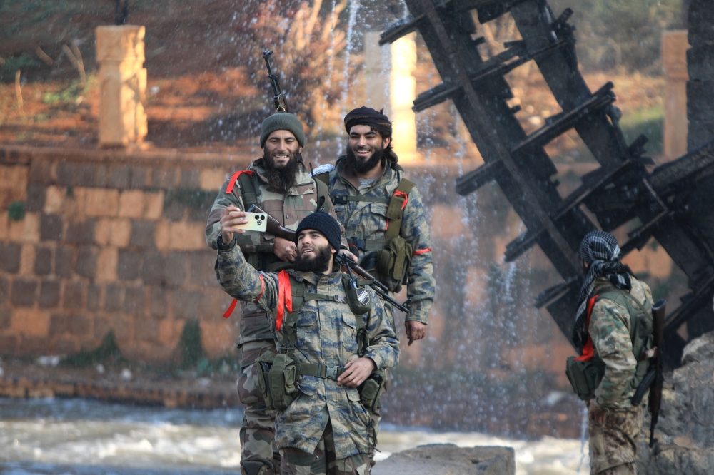 Anti-government fighters pose for a selfie picture in one of Hama’s water wheels. — AFP pic