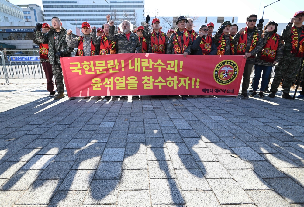 South Korean marine veterans hold a banner reading ‘Let's behead Yoon Suk Yeol!’ during a protest calling for the resignation of South Korea's President Yoon Suk Yeol near the Presidential Office in Seoul on December 5, 2024. — AFP pic