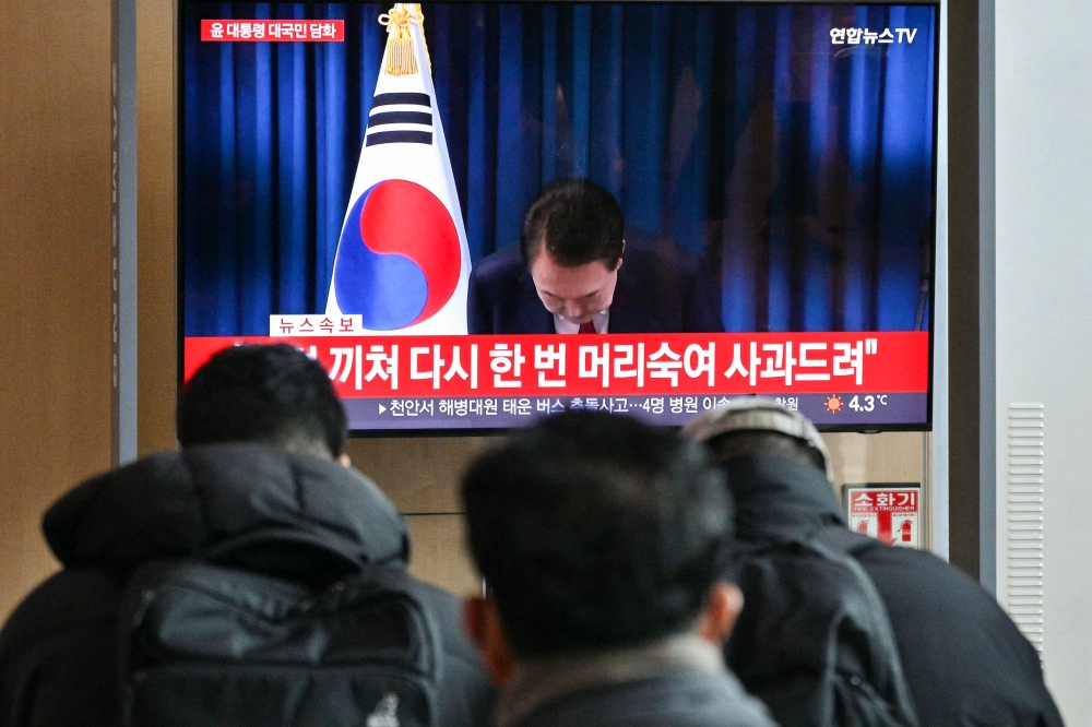 People watch a live television broadcast of South Korea's President Yoon Suk Yeol bowing after the end of his address, at a train station in Seoul December 7, 2024. — AFP pic