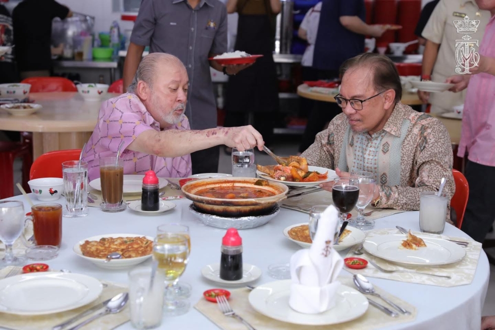 His Majesty Sultan Ibrahim portions out food to Prime Minister Datuk Seri Anwar Ibrahim (right) at Kedai Makan Jadi Baru Botak in Tanjung Puteri, Johor Baru on Dec 9, 2024. — Picture courtesy of HRH Crown Prince of Johor Facebook