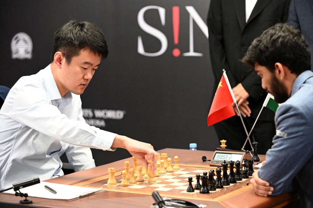 China's chess grandmaster Ding Liren (left) and India's grandmaster Gukesh Dommaraju (right) compete in game 14 of the 2024 FIDE World Championship in Singapore on December 12, 2024. — AFP pic