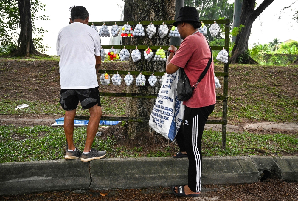 People browse recycled golf balls put up for sale near a golf course in Shah Alam, Selangor, on Nov 16, 2024.  — AFP pic