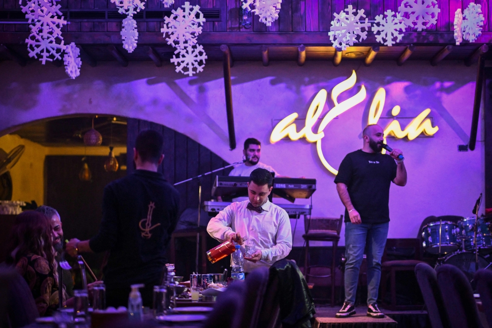 A waiter serves whisky to diners at a restaurant in Damascus on December 13, 2024. — AFP pic