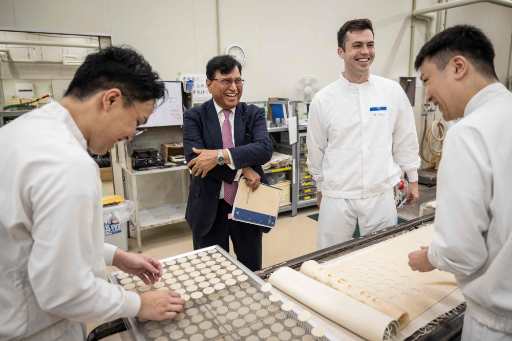 Lekh Juneja (2nd left), chairman and CEO of Kameda Seika, chatting with employees as they make rice crackers sample at the testing centre of the company’s headquarters in Niigata city, Niigata prefecture August 5, 2024. — AFP pic