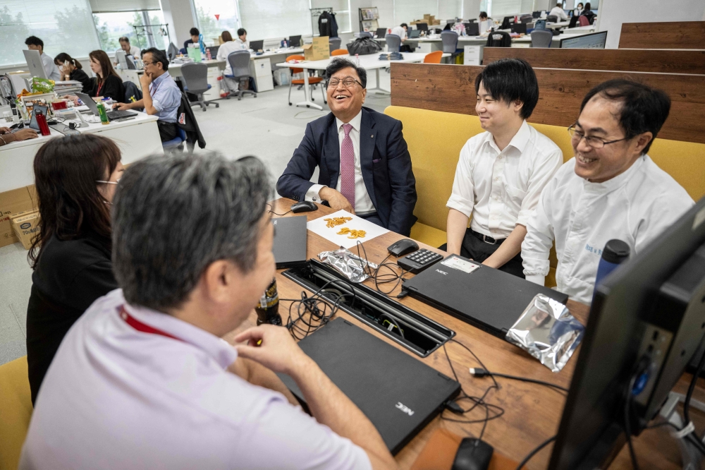 Lekh Juneja (C), chairman and CEO of Kameda Seika, chatting with employees while testing samples of rice crackers at the company’s headquarters in Niigata city, Niigata prefecture August 5, 2024. — AFP pic