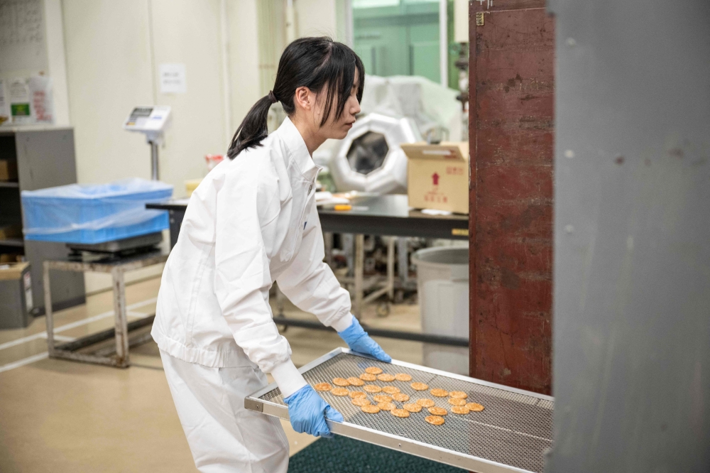 A Kameda Seika employee making rice crackers samples at the testing centre of the company’s headquarters in Niigata city, Niigata prefecture August 5, 2024. — AFP pic