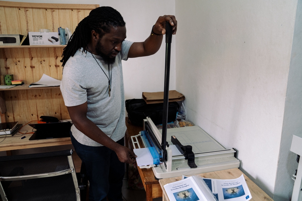 Co-founder of the production company Nyiragongo Ngoma Production Martin Lukongo cuts paper for the printing of the book ‘J’irai danser sur la tombe de Senghor’ written by Blaise Ndala and republished by Mlimani Editions in the printing department of the production company in Goma, in the east of the Democratic Republic of Congo, on November 15, 2024. — AFP pic