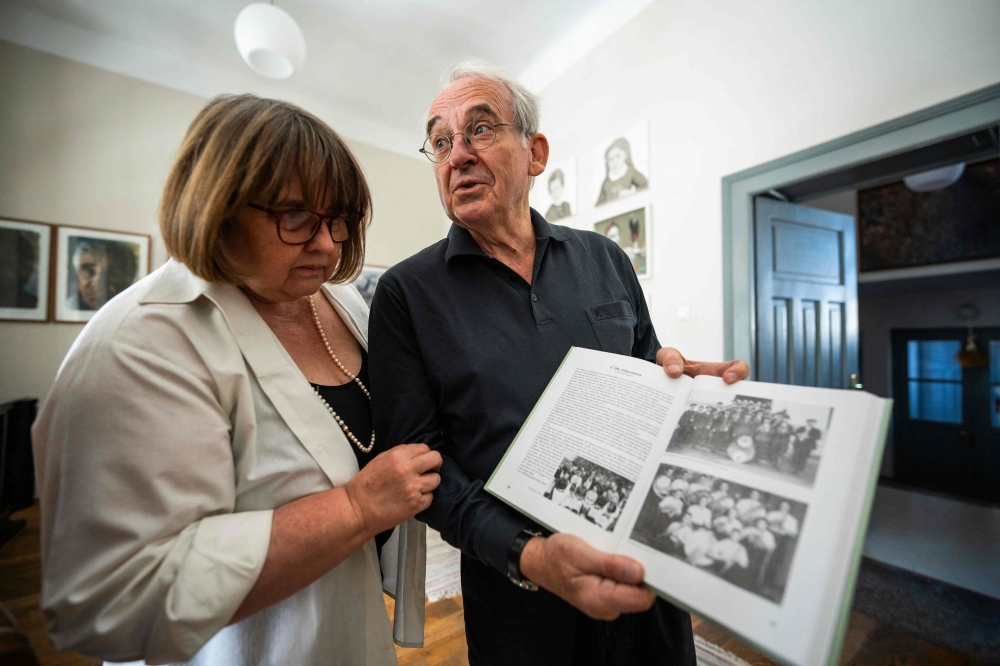 Michael Lisske (right) and his wife, Carmen Schuster, look at a book with old pictures taken in Cincsor a small Transylvanian village some 250km north-west of Bucharest October 17, 2024. — AFP pic