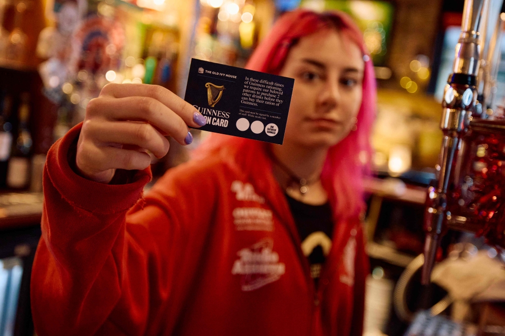 A member of staff holds up a ‘Guinness Ration Card’ behind the bar inside The Old Ivy House public house in Clerkenwell, London December 15, 2024. — AFP pic