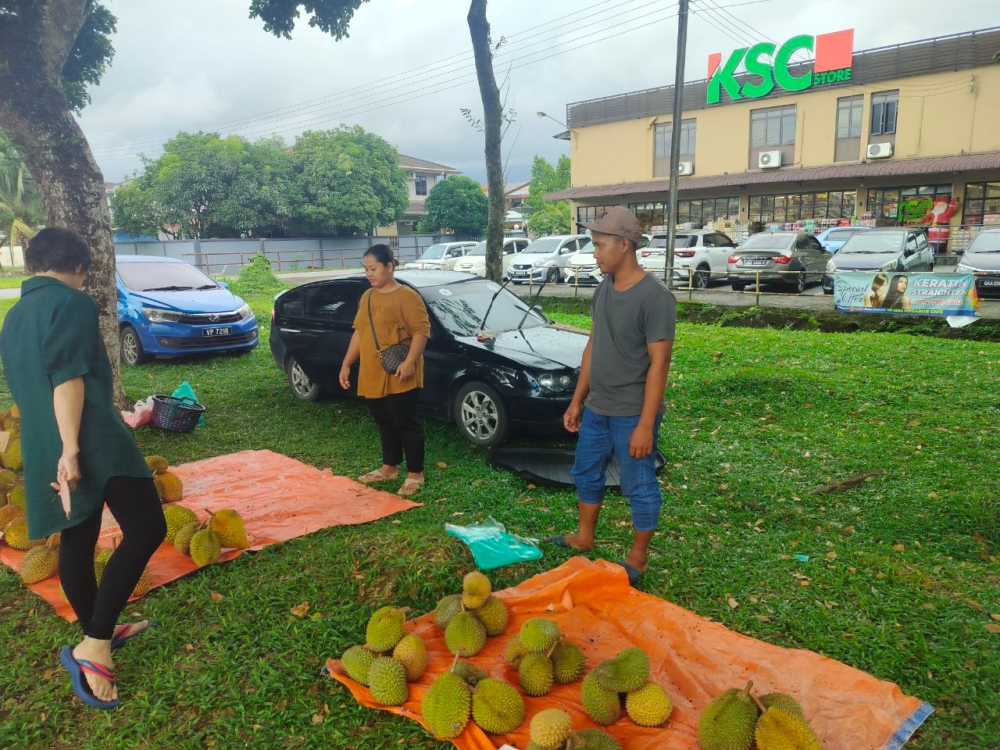 (From right) Rezuan and Dillah at their stall, situated across the KSC Store. — The Borneo Post pic