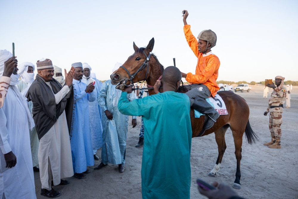 A jockey holds up the key to the motorcycle he won after placing first during the first race of the season at the Biligoni racecourse in Chad on November 30, 2024. — AFP pic 