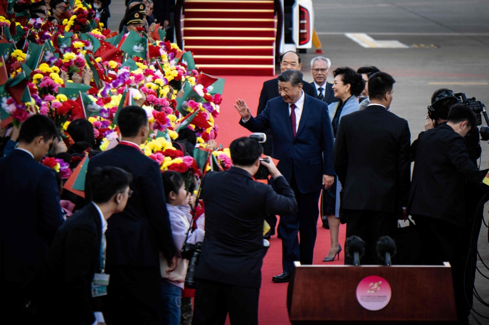 China’s President Xi Jinping greets children waving the flags of China and Macau upon his arrival at Macau’s international airport in Macau on December 18, 2024, ahead of celebrations for the 25th anniversary of the city's handover from Portugal to China. — AFP pic 