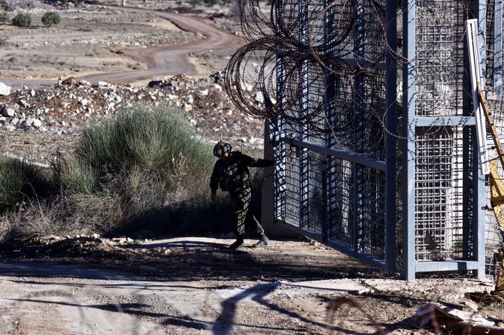 An Israeli soldier closes a gate on the Golan Heights side of the ceasefire line with Syria, as seen from Majdal Shams in the Israeli-occupied Golan Heights, December 19, 2024. — Reuters pic