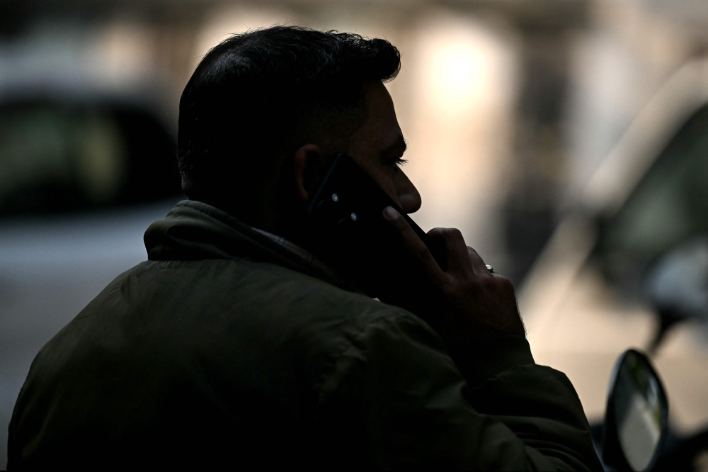 In this photograph taken on December 9, 2024, a field detective speaks on his mobile phone before leaving for an assignment, in New Delhi. — AFP pic