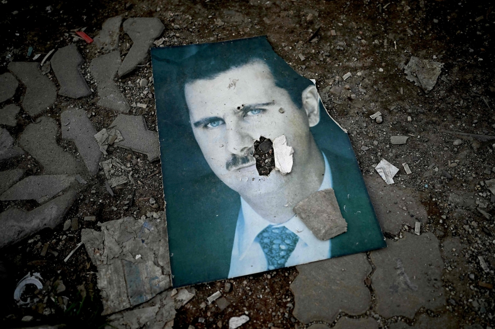 A damaged portrait of Syria’s ousted president Bashar al-Assad lies on the ground in the western Syrian port city of Latakia on December 15, 2024. — AFP pic