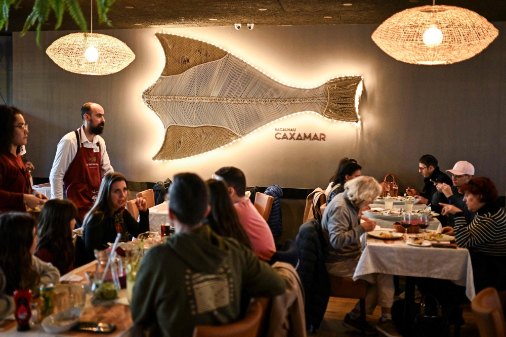 Customers enjoying a meal at a restaurant specialising in traditional cod-based recipes in Lisbon. — AFP pic