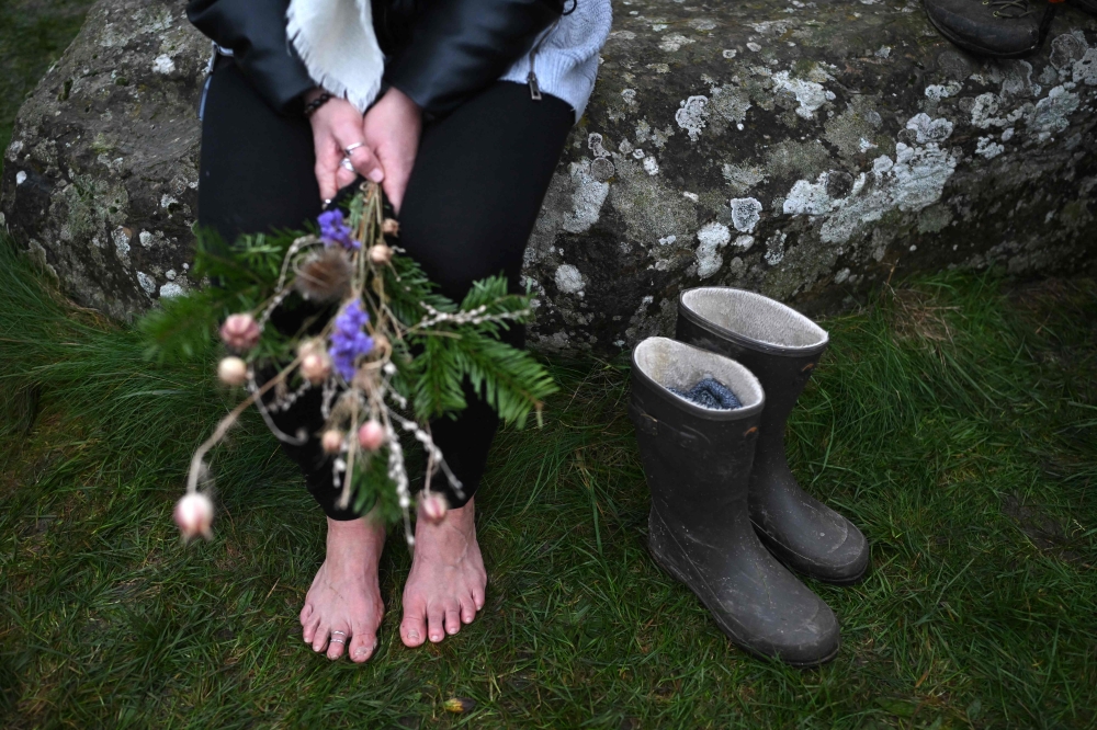 A bare-footed reveller takes a break as people gather to celebrate the pagan festival of 'Winter Solstice' at Stonehenge in Wiltshire in southern England on December 21, 2024. — AFP pic