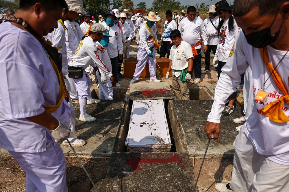 Volunteers dig up the remains of unclaimed bodies. — Reuters