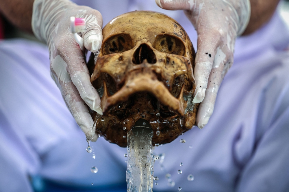 A volunteer cleans a human skull with holy water known as ‘tea water’. — Reuters