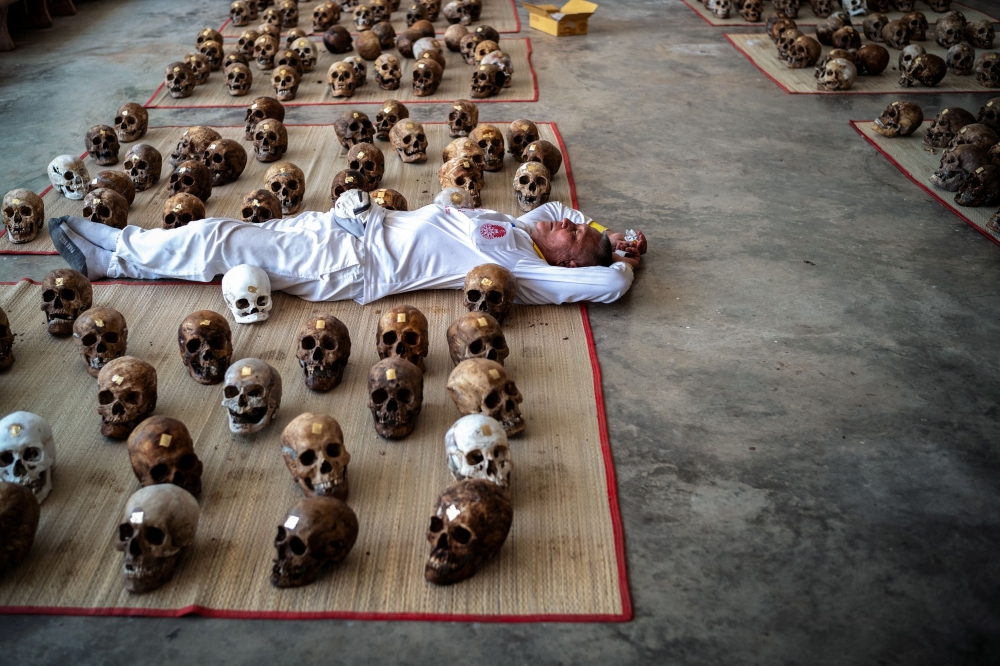 A volunteer rests beside human skulls. — Reuters