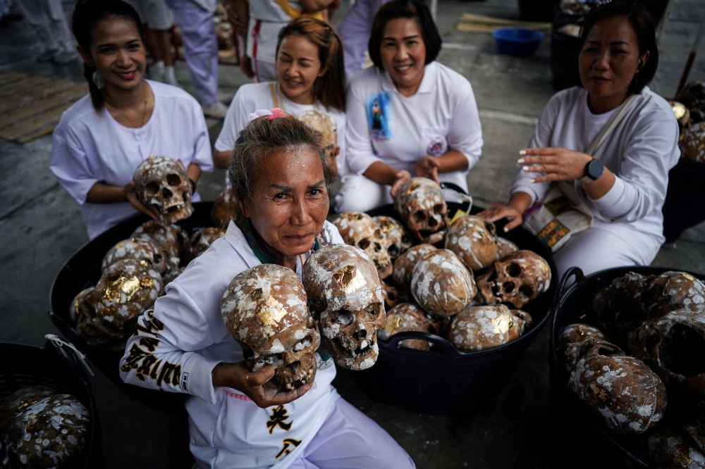 Tonploy Boonporn, known as Ploy (front), 63, holds human skulls as she poses for a photo with her friends. — Reuters