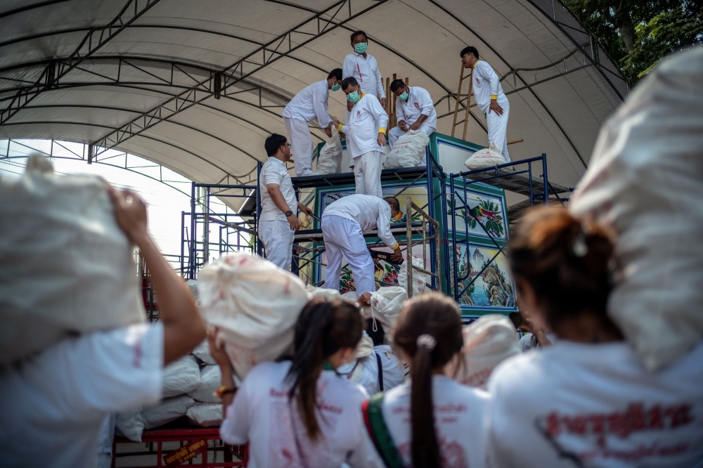 Volunteers carry bags containing the bones of unclaimed bodies to place them inside a funeral pyre for cremation. — Reuters