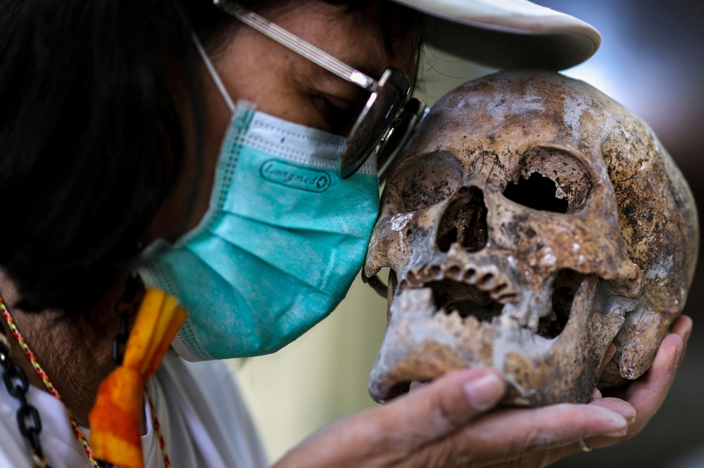 Retired teacher Termsuk Rongmarut, 67, pays respects to a skull from an unclaimed body. — Reuters