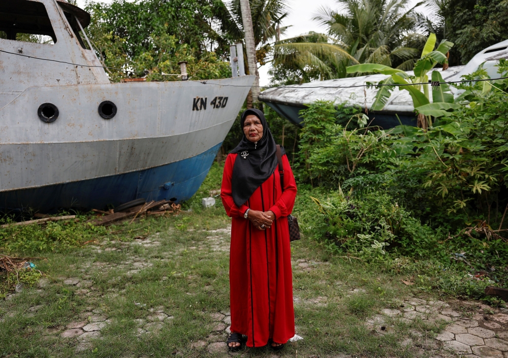 Saudah poses for pictures in front of coast guard ships that were carried about five kilometres inland near her house in the city center of Banda Aceh December 21, 2024. — Reuters pic