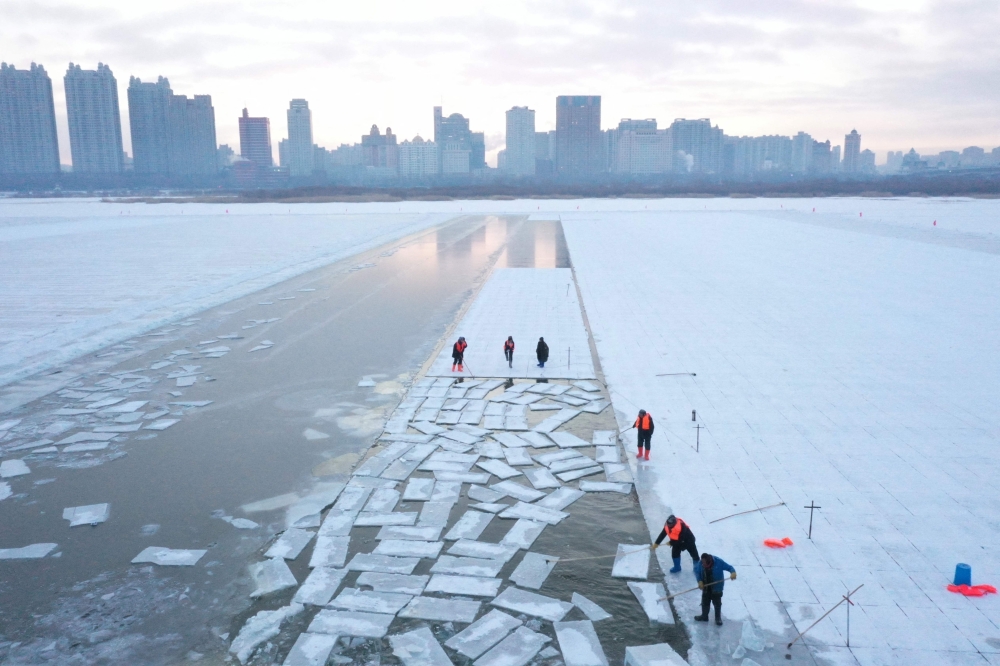 This aerial picture shows workers harvesting ice from the frozen Songhua river in preparation for the annual Harbin Ice and Snow World Festival December 17, 2024. — AFP pic