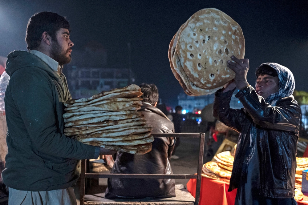 Afghan vendors selling traditional flatbreads locally known as Naan, at a roadside market in Kabul December 16, 2024. — AFP pic