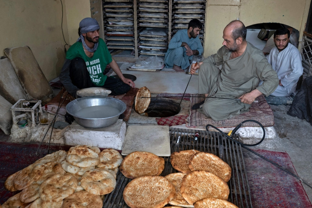 Afghan baker Jamil Ghafori (left) prepares traditional flatbreads locally known as Naan, at a bakery in Kabul November 27, 2024. — AFP pic