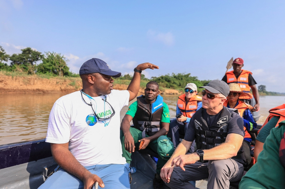 Aristide Takoukam Kamla (left), a marine biologist, researcher and conservationist specialising in the African manatee, talks to tourists and other biologists on a boat in Dizangue, on December 10, 2024. — AFP pic 