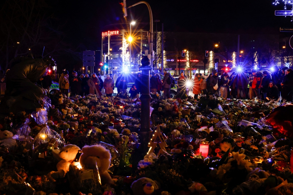 People look at flowers and candles left as a tribute for the victims of the 'Alter Markt' Christmas market, after a man drove a car into the crowd through an emergency exit route on Friday evening, in Magdeburg, Germany, December 23, 2024. — Reuters pic  