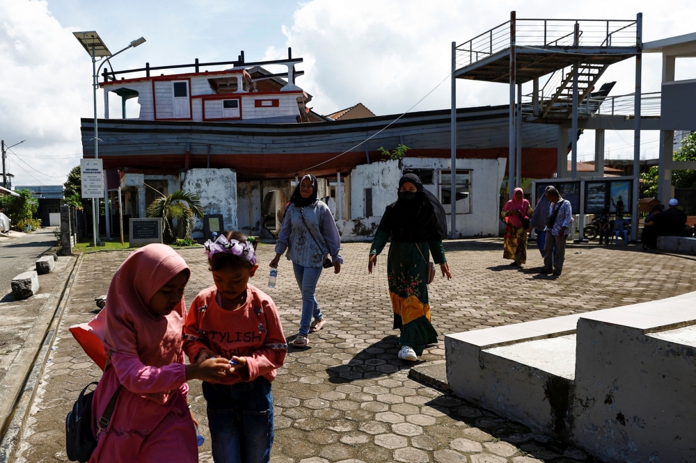 People visit a tsunami memorial site where a wooden boat was swept onto a roof by the Indian Ocean tsunami in 2004, in Lampulo, Banda Aceh, Aceh, Indonesia, December 25, 2024. — Reuters pic