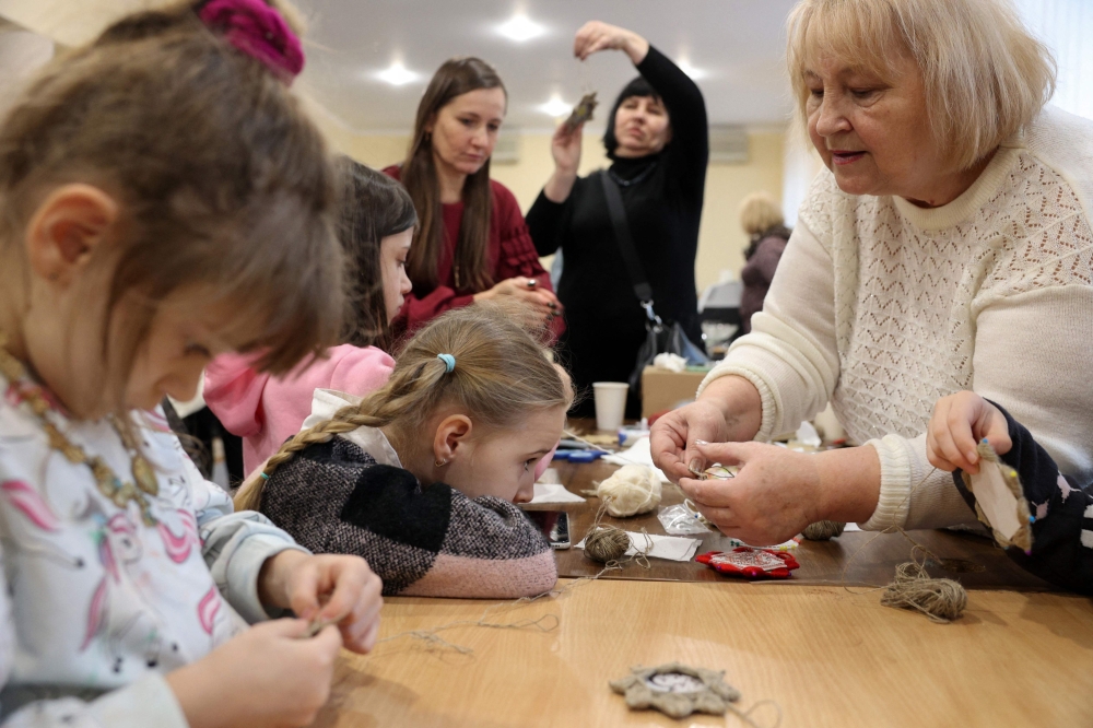 Head of the Feliks Theater Studio of the Bakhmut People's House Tetyana Salieva (right) leads a masterclass on making Christmas decorations with members of the diaspora from Bakhmut before a Christmas concert organised by the exiled Bakhmut city hall in Kyiv, on December 23, 2024. — AFP pic