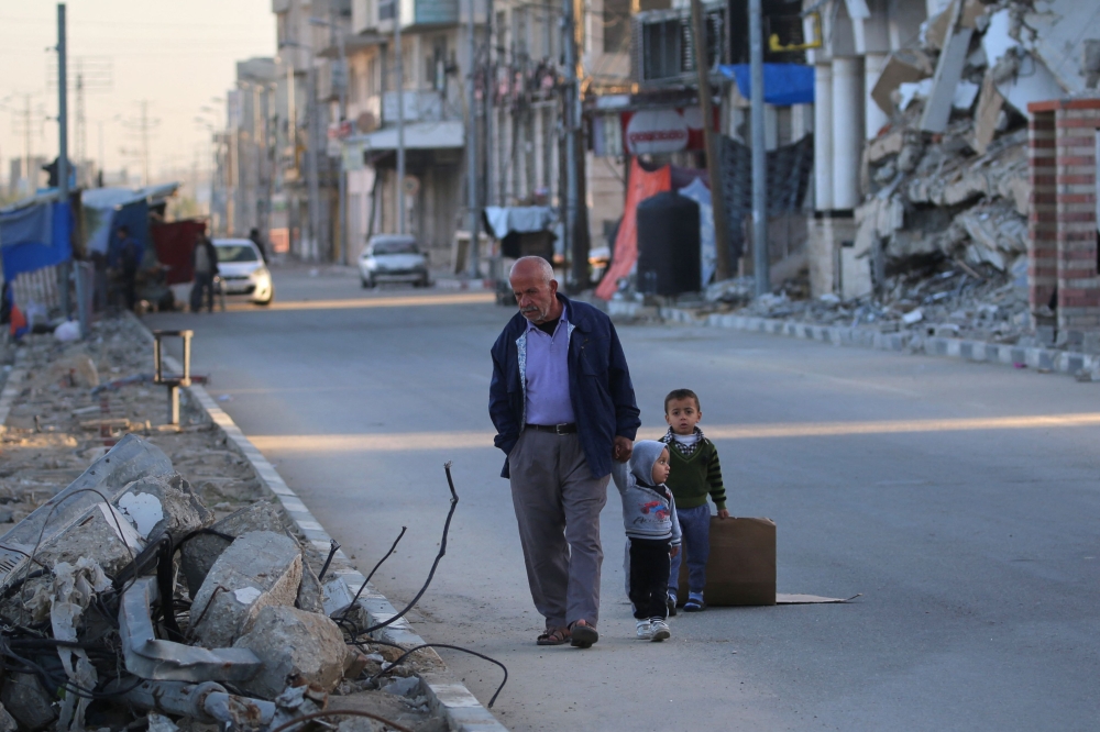 A Palestinian man walks with children in Deir el-Balah in the central Gaza Strip, on December 24, 2024, amid the ongoing war between Israel and the Palestinian militant group Hamas. — AFP pic