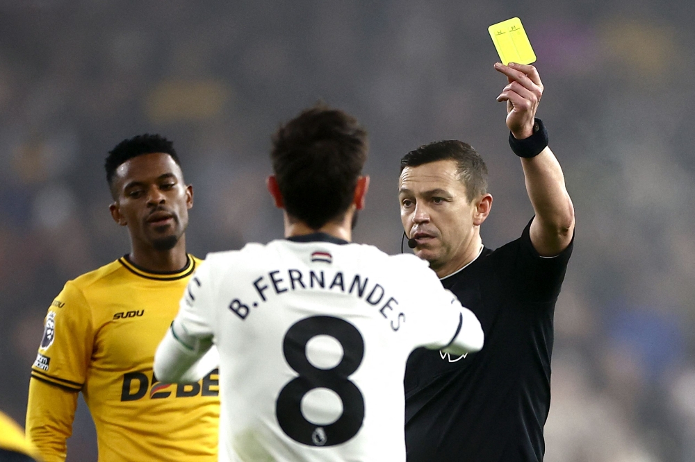 Referee Tony Harrington showing a yellow card to Manchester United’s Bruno Fernandes during the match against Wolverhampton Wanderers.  — AFP