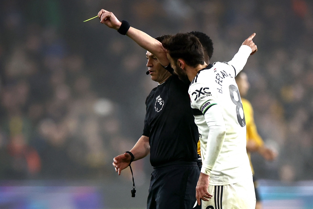 Manchester United’s Bruno Fernandes talks to referee Tony Harrington. The captain was sent off after just two minutes into the second half.— AFP 