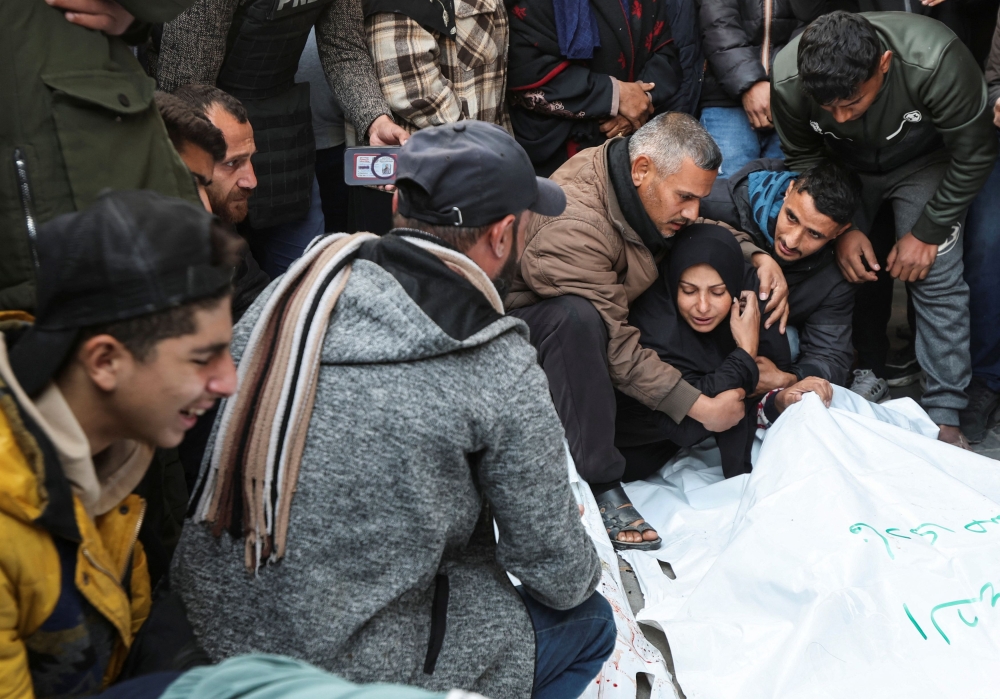 Mourners gather beside the bodies during the funeral of Palestinian journalists from Al-Quds Al-Youm television channel who were killed in Israeli airstrikes, according to medics with the Gaza health authorities, amid the Israel-Hamas conflict, in Nuseirat, central Gaza strip, December 26, 2024. — Reuters pic 