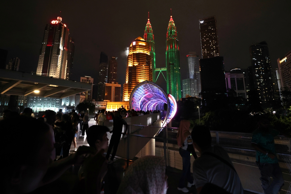 The public spending time at the Saloma Link with Petronas Twin Towers (KLCC) in the background, illuminated in red and green on a public holiday in celebration of Christmas, December 25, 2024. — Bernama pic 