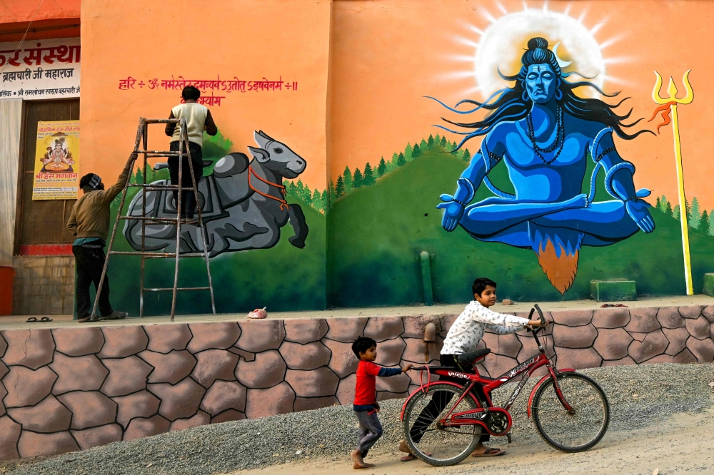 Children walk past a graffiti of Lord Shiva near the banks of river Ganges, ahead of the Maha Kumbh Mela festival in Prayagraj on December 18, 2024. — AFP pic