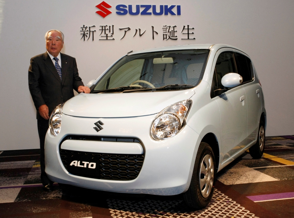 Suzuki Motor Corp Chairman and CEO Osamu Suzuki poses next to the company’s new ‘Alto’ car during an unveiling in Tokyo December 16, 2009. — Reuters pic